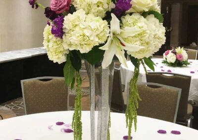Modern floral arrangement with white, purple, and pink flowers in a tall vase at an event venue; fresh flowers delivery in Orange County.