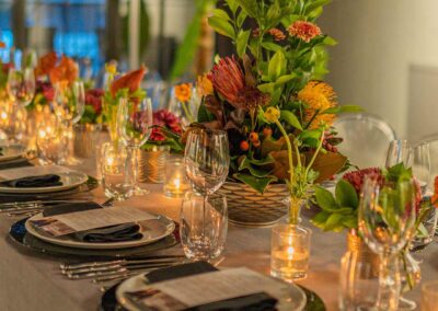 Elegant dining table setting with floral centerpieces, candles, glassware, and place settings prepared for a special event or dinner party.