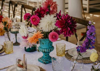 Modern floral arrangement in turquoise vase on a decorated table for a social event.