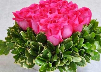 A floral arrangement consisting of a cluster of pink roses in full bloom, forming a dome-like shape.
