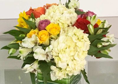 Modern floral arrangement in a glass vase with colorful roses and white flowers by a florist in Orange County.