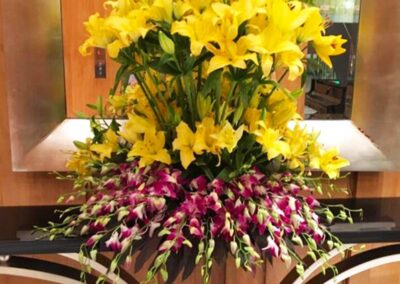 Elegant floral arrangement with yellow lilies and purple orchids; perfect for weddings, corporate/social events in Orange County.
