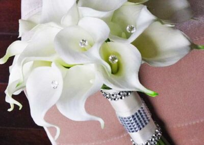 Modern white floral arrangement with calla lilies, adorned with rhinestones, ideal for weddings or events. Florist Orange County.