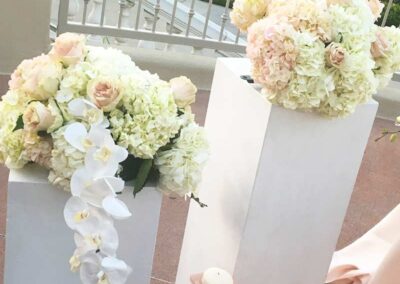 a sophisticated floral arrangement, lush bouquets of pale pink and white flowers, featuring roses and hydrangeas, with cascading white orchids extending to one side.