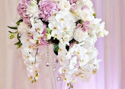 A luxurious floral arrangement consisting of a variety of flowers including lush purple hydrangeas, delicate pink roses, pristine white roses, and cascading white orchids.