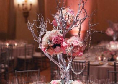 A floral arrangement consisting of blue and white flowers, with some smaller yellowish-white blooms interspersed throughout. The flowers are accented with a bright blue ribbon and delicate white netting or tulle.