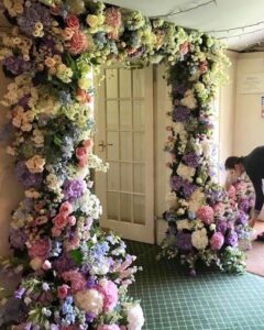 A professional designing a square floral arch.